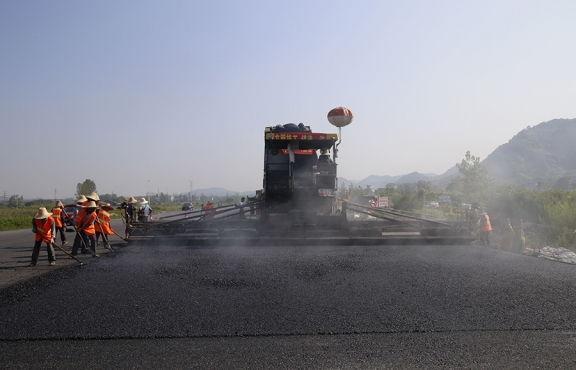 2019年8月，宜春經(jīng)開區(qū)S311路面攤鋪現(xiàn)場(chǎng)，工友們輔助路面兩側(cè)的分料、補(bǔ)窩等作業(yè)